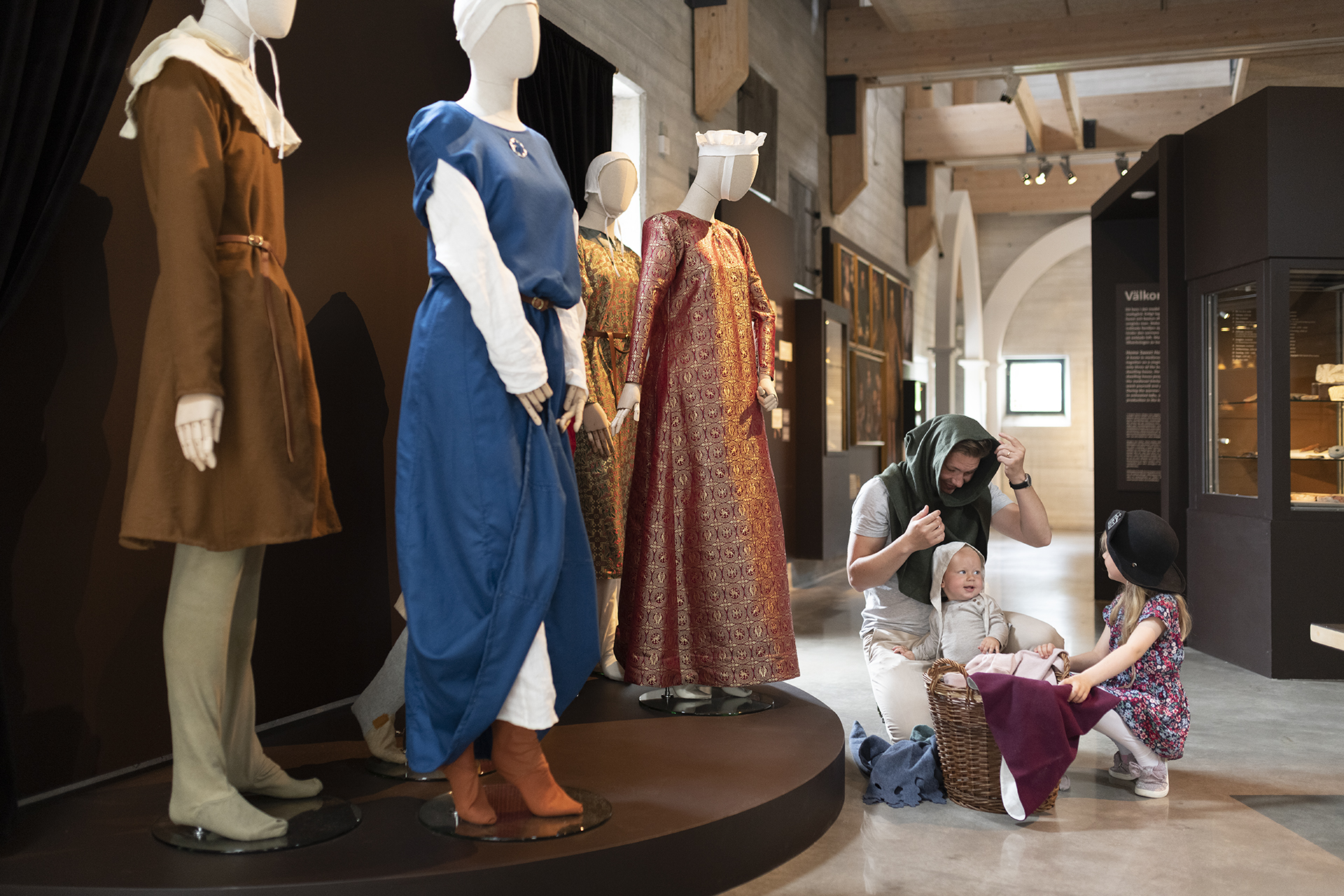 A man with two small children are trying out medieval head wear