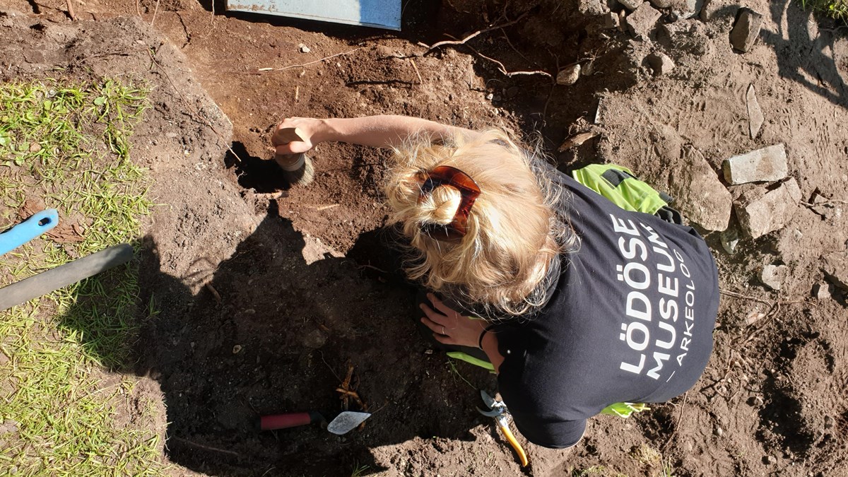 En arkeolog gräver med pensel i ett schakt