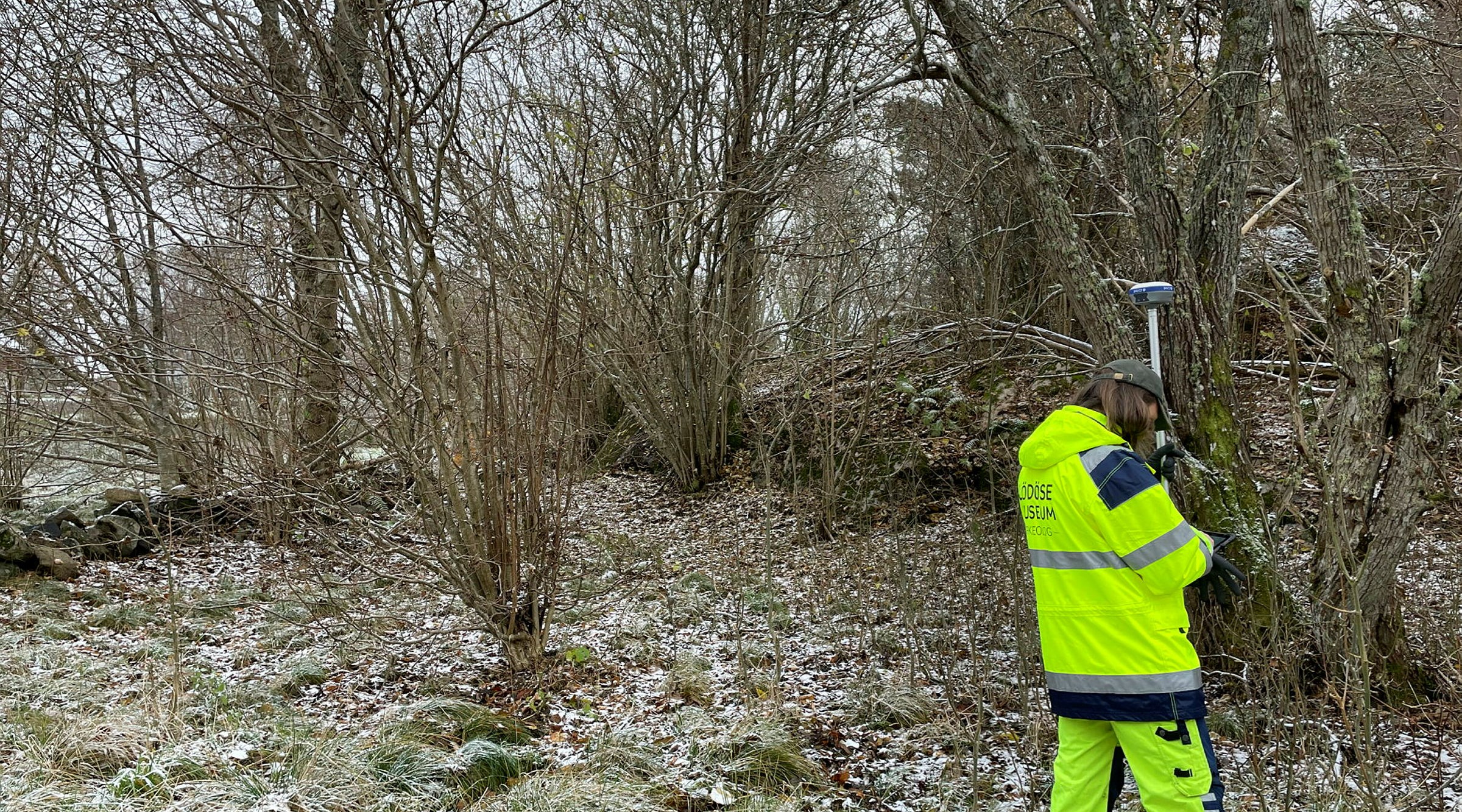 En arkeoloh står i ett snårigt viinterlandskap och mäter med GPS-utrutning