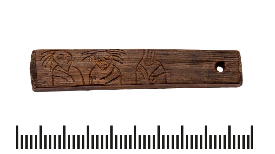 A wooden stick with inscriptions of human figures