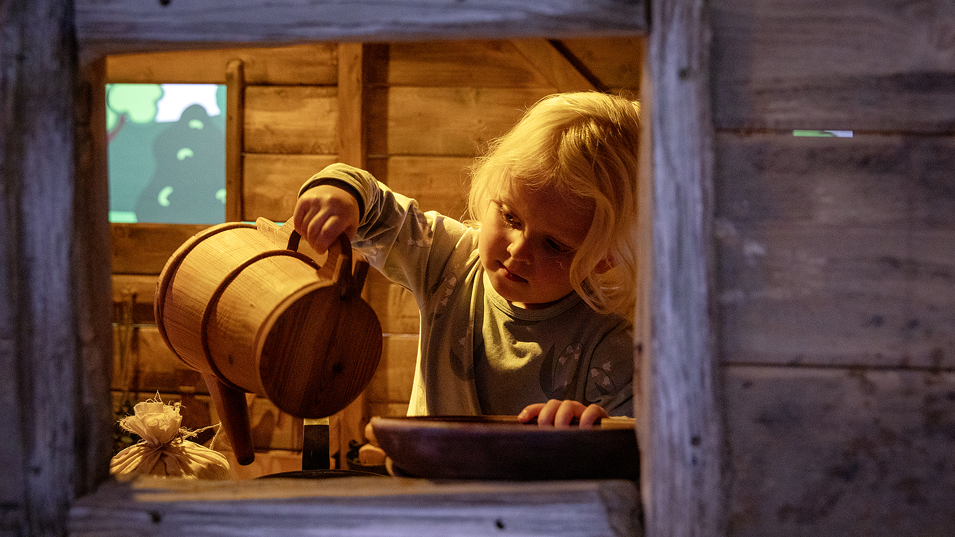 Ett barn står i ett trähus och leker