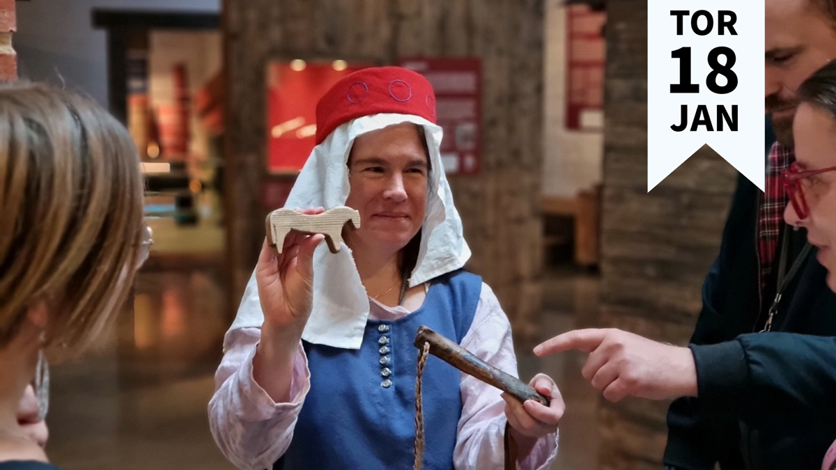 En museipedagog i medeltida klädselvisar föremål för publik