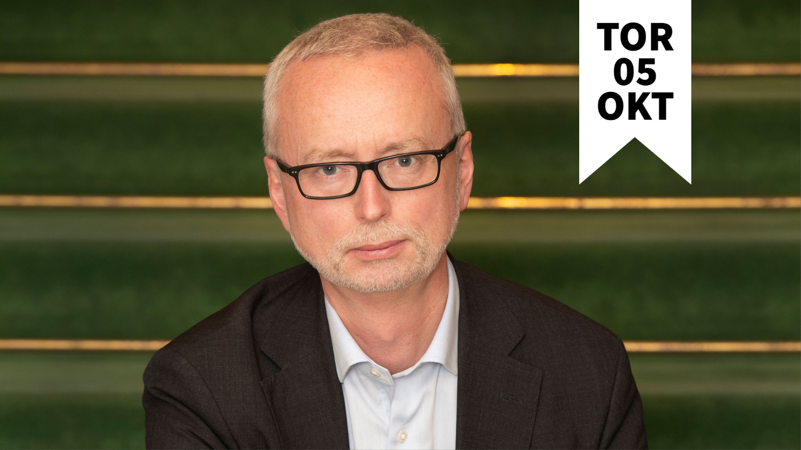 En porträttbild på en man i kostym och glasögon