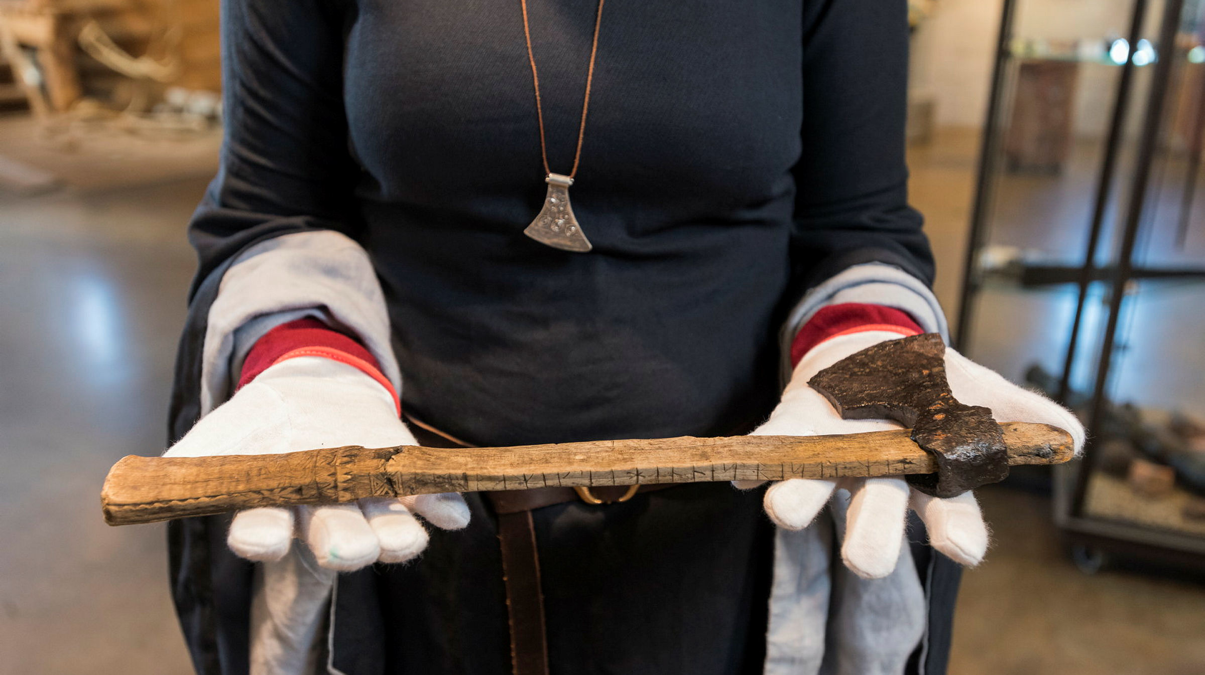 En kvinna i medeltida kläder håller fram en medeltida runyxa.