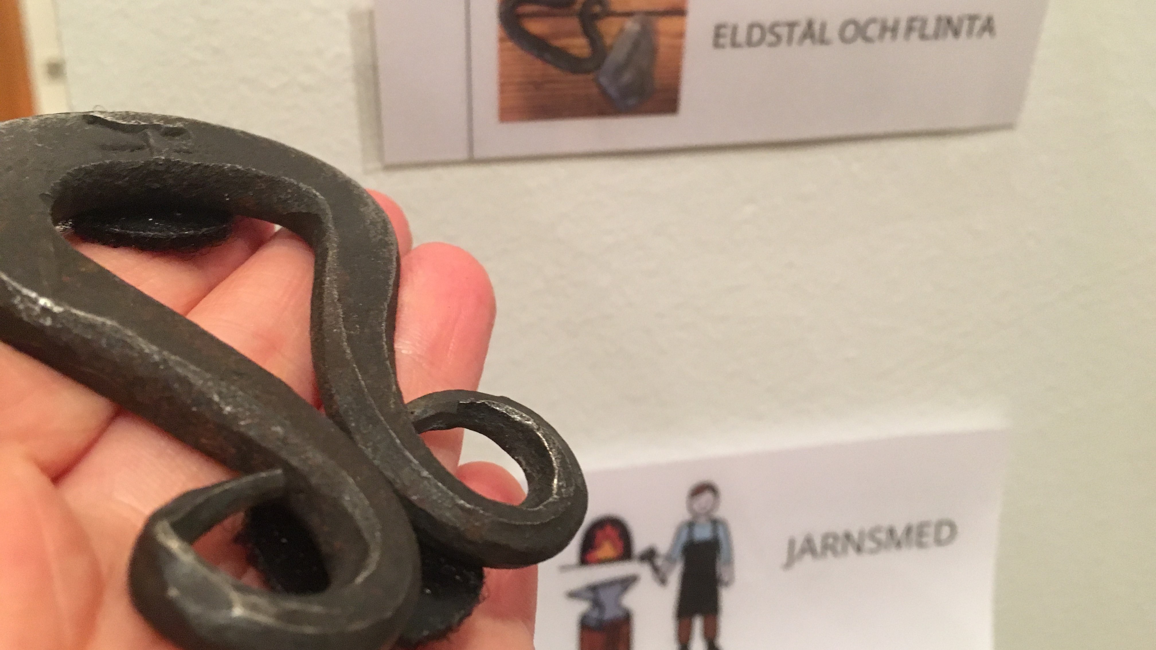 I förgrunden finns ett eldstål och i bakgrunden bilder med text