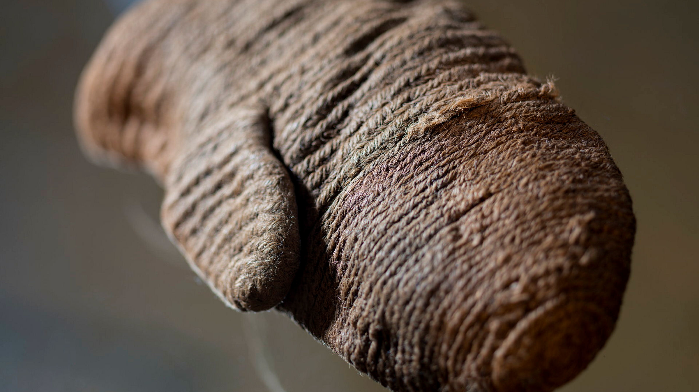 Vante i ett garn som ser ut som vanligt, brunt rep. Den är tillverkad i en teknik som heter nålbindning. 