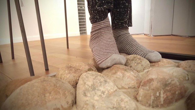 Ett par fötter med randiga strumpor rör sig över några stenar.