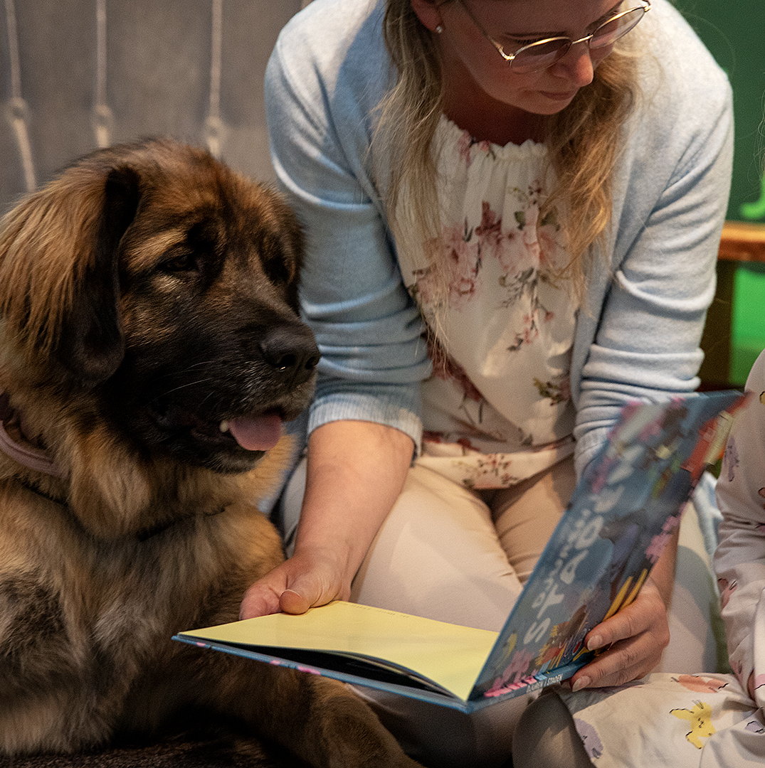 En kvinna, barn och en hund läser en bok