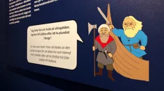 En närbild på en av skyltarna i utställningen. På bilden syns två tecknade figurer som ska föreställa vikingar, med en pratbubbla.