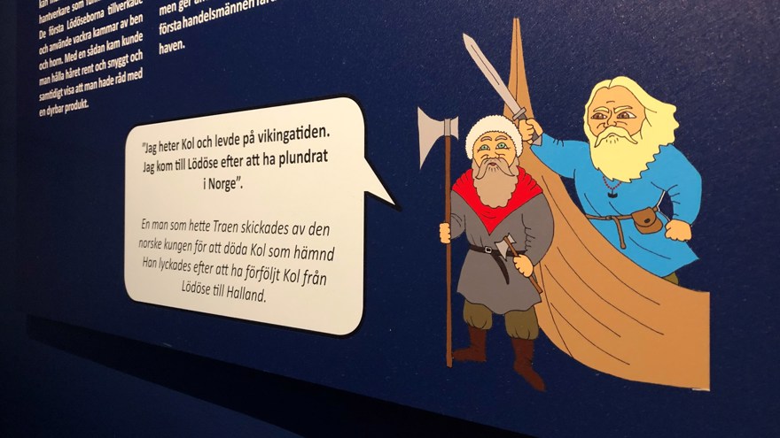 En närbild på en av skyltarna i utställningen. På bilden syns två tecknade figurer som ska föreställa vikingar, med en pratbubbla.