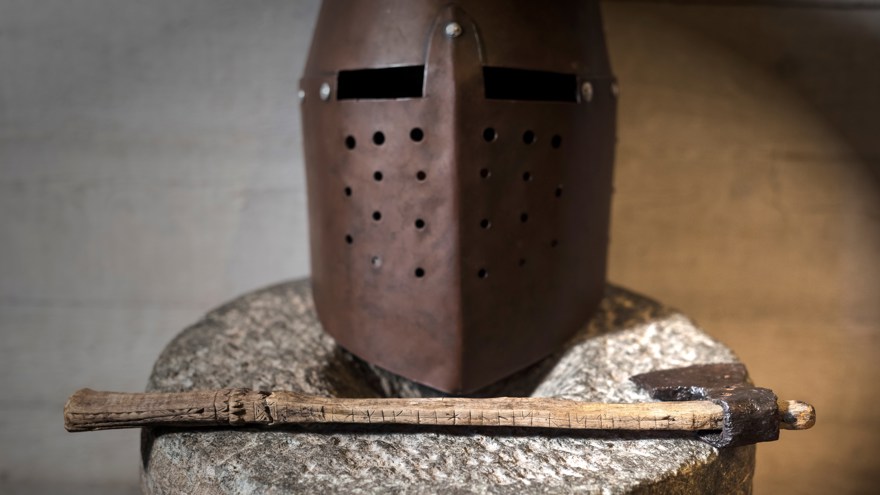 En riddarhjälm med en yxa som ligger framför.