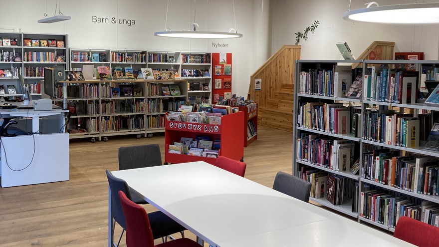 Ett rum i ett bibliotek med bokhyllor, bord och stolar