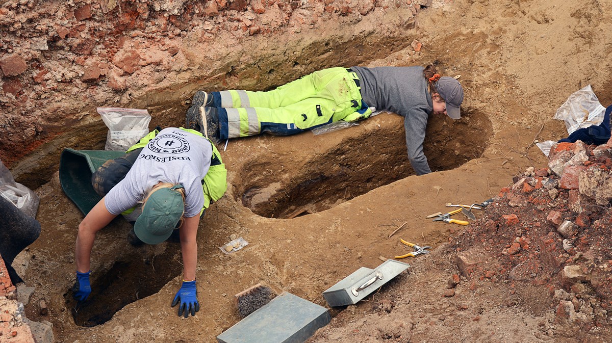 Två arkeologer gräver i varsin grop