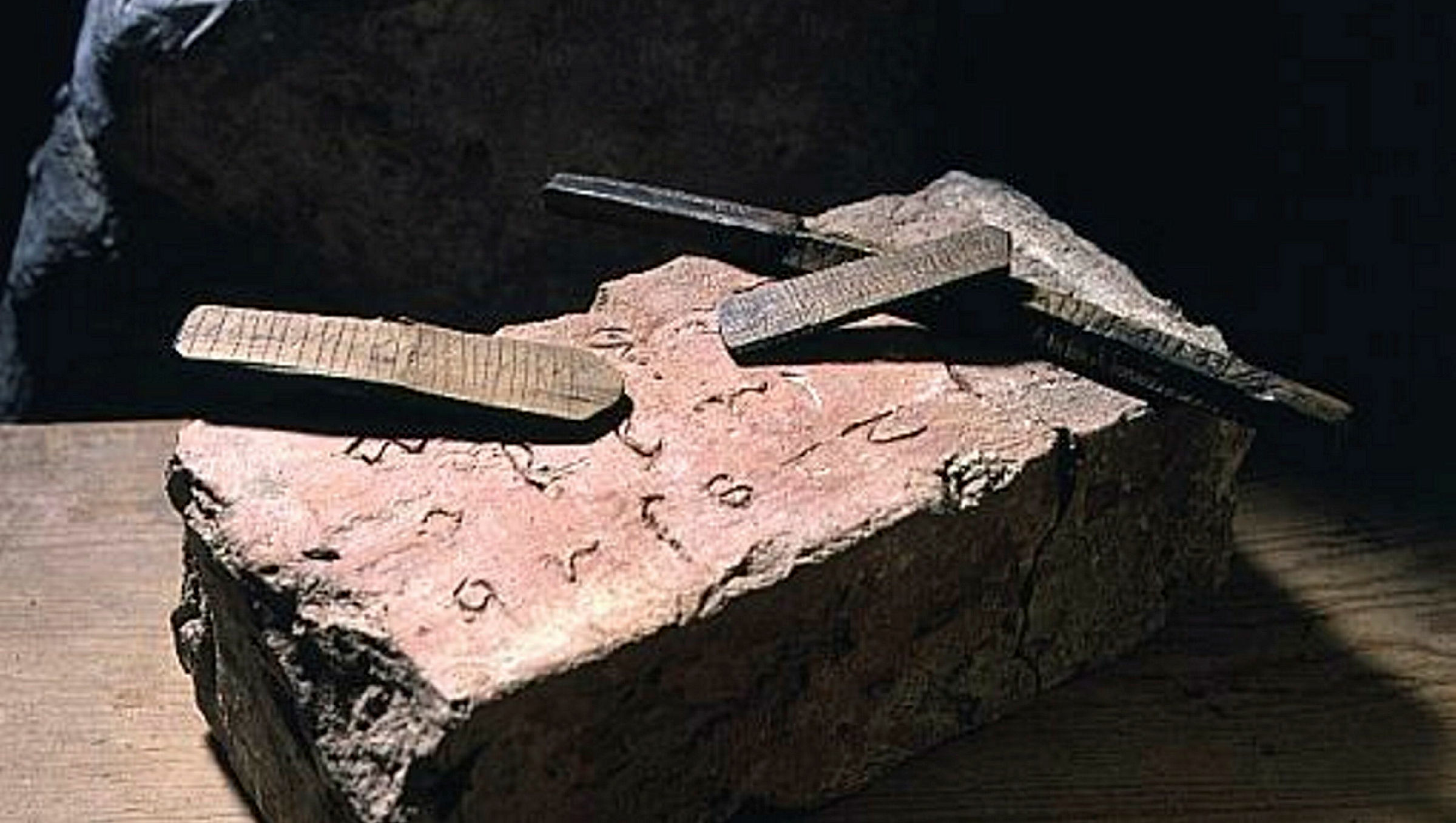 A brick with the latin alphabet and three wooden sticks with runes inscribed