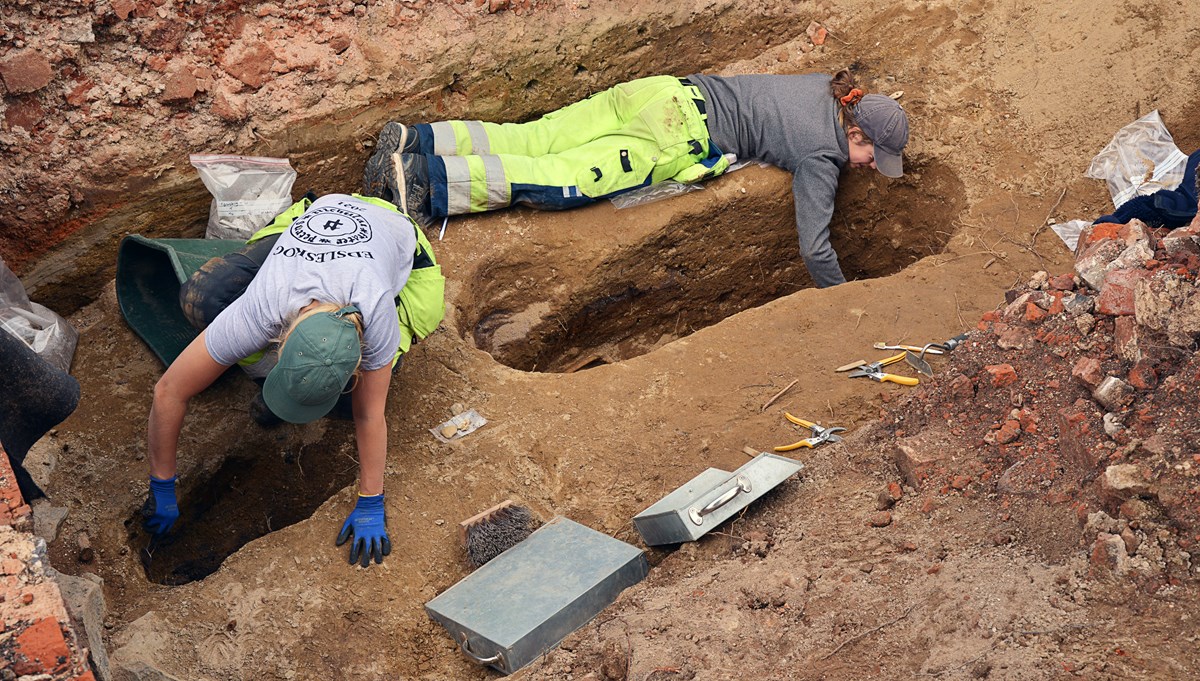Två arkeologer gräver i jorden 