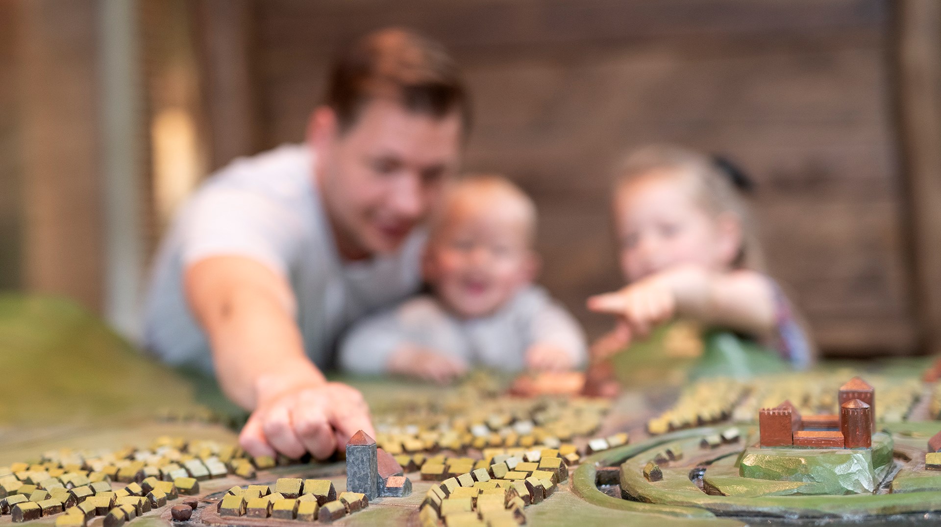 En vuxen och barn tittar och känner på en modell över en medeltida stad