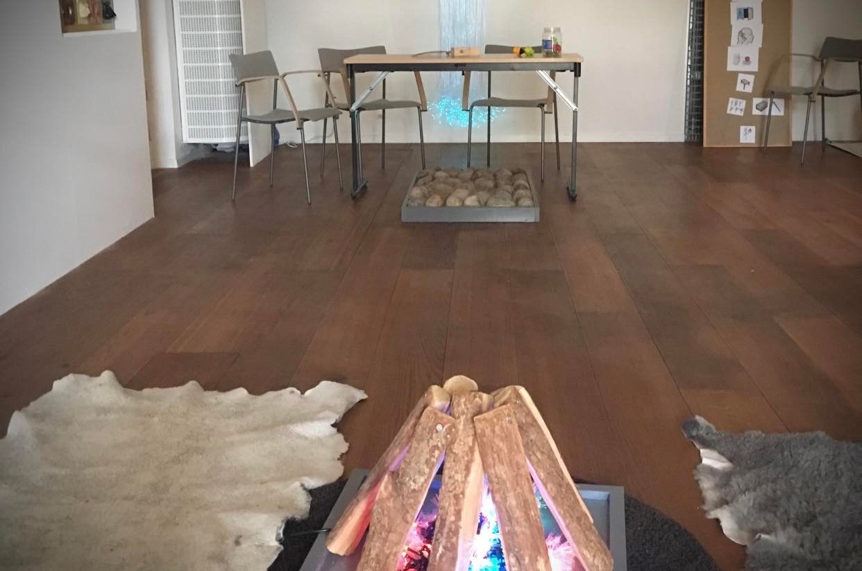 En överblick över sensoriska rummet. I förgrunden syns en låtsaseld. I bakgrunden syns bord och stolar och en platta med kullersten på golvet.